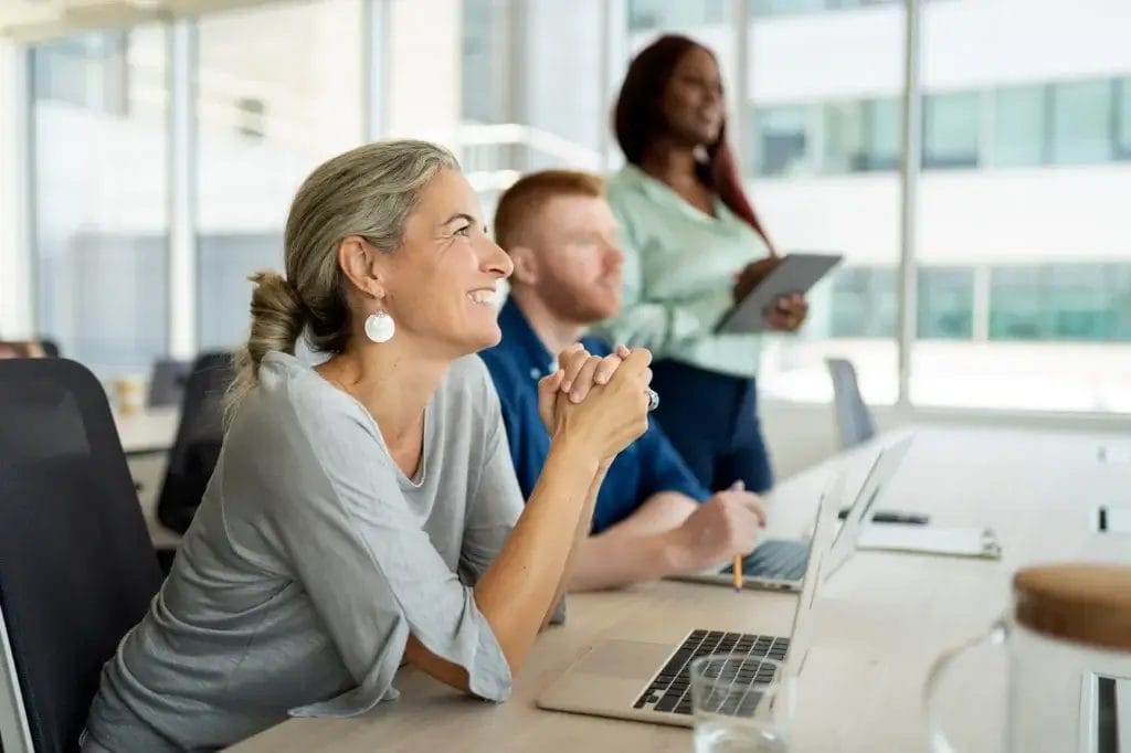A team sitting around a table during a workplace stress management workshop, smiling and engaged in discussion.